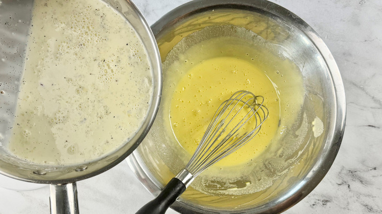 Vanilla cream mixture going into egg mixture in bowl with whisk
