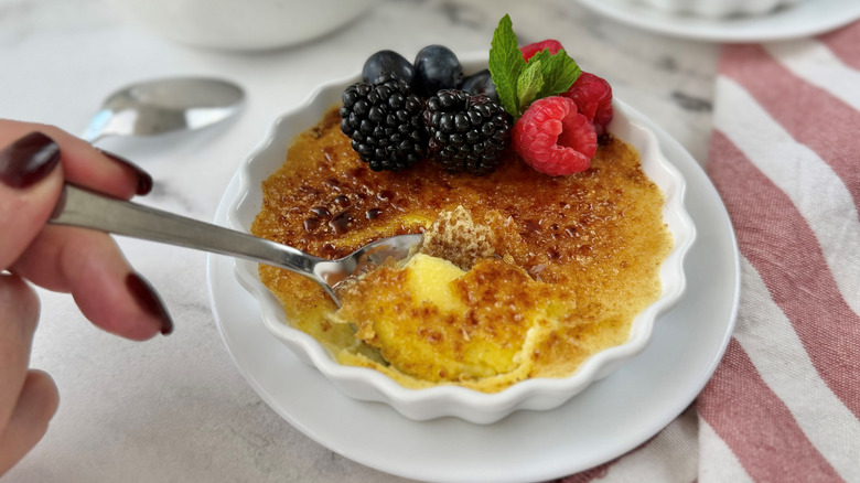 Spoon removing bite from crème brûlée ramekin