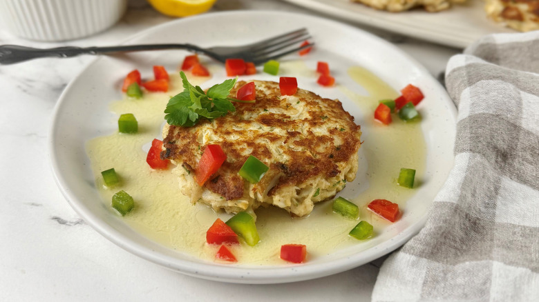 Crab cake with diced peppers on plate