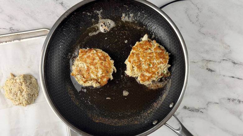 Crab cakes cooking in pan