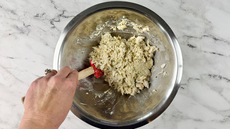 Hand mixing crab cake mixture with spatula