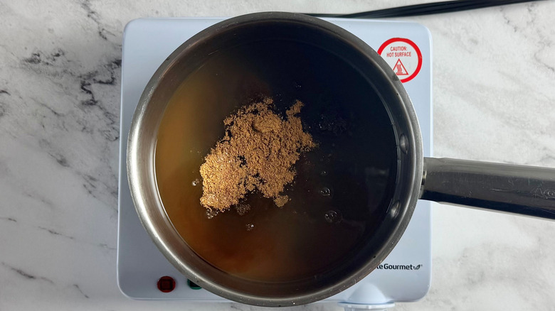 brown sugar and water in a metal pot on a hot plate