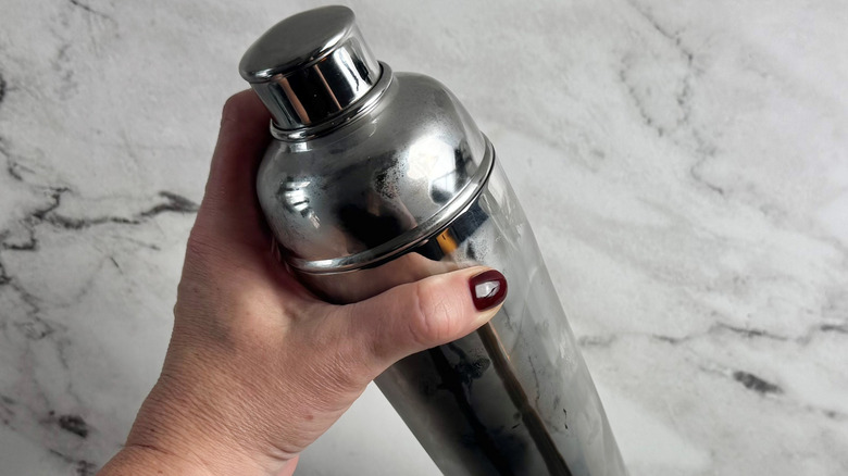 hand holding a lidded metal tumbler