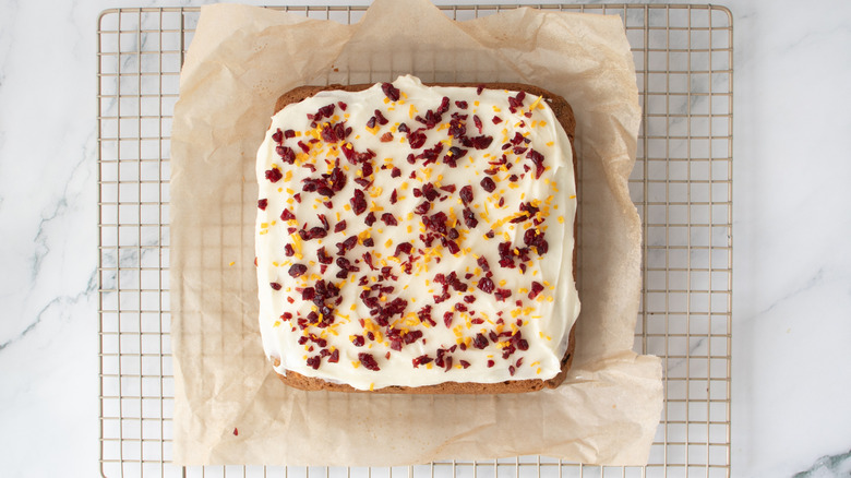 uncut bar cookie with white frosting and dried cranberries