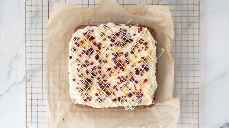 uncut bar cookie with white frosting and dried cranberries