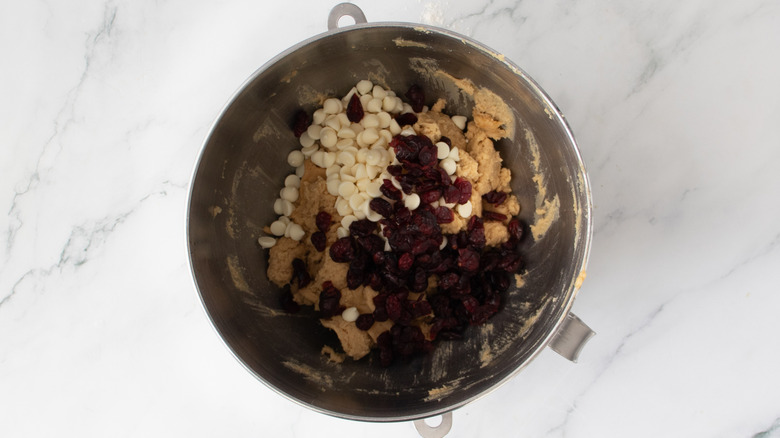 craisins and white chocolate chips on top of raw cookie dough