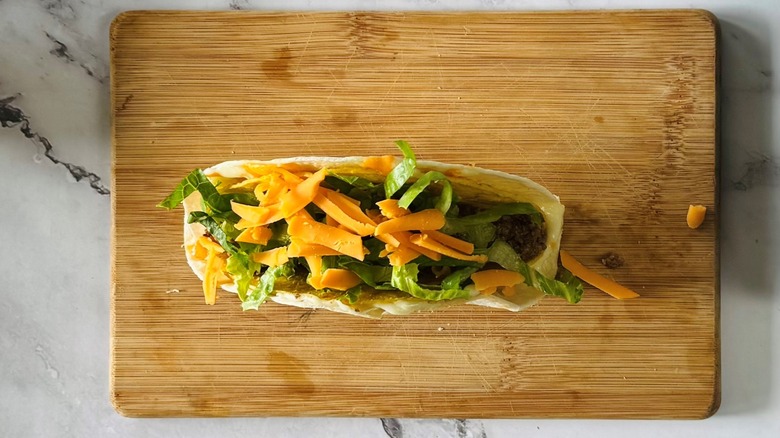 tortilla-wrapped taco with ground beef, lettuce, and cheese