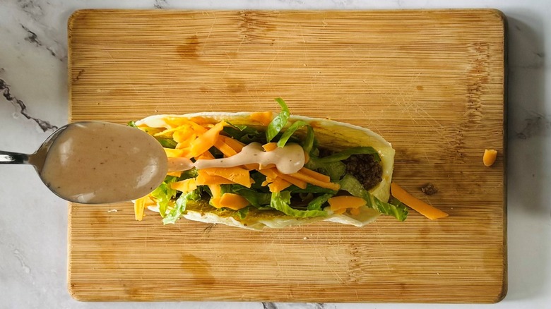 spoonful of sauce hovering over a tortilla-wrapped taco