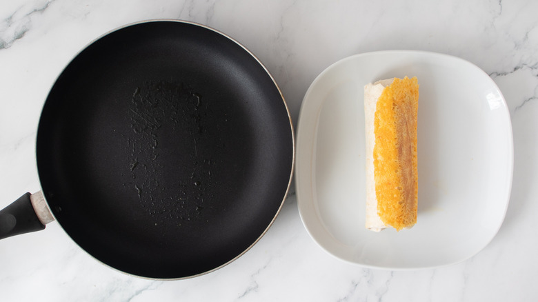 orange and white burrito next to a black frying pan