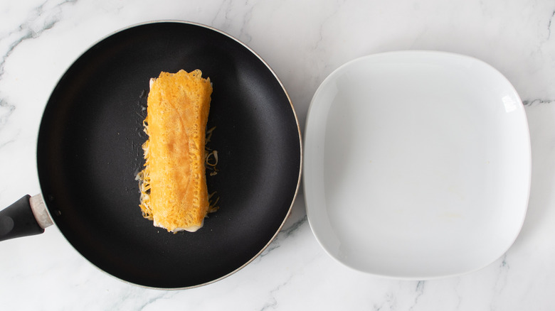 orange-colored burrito in a black frying pan