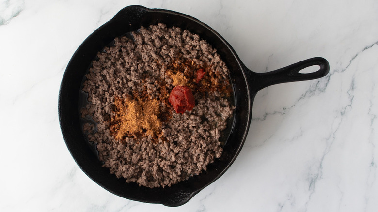 Ground beef with seasonings in skillet