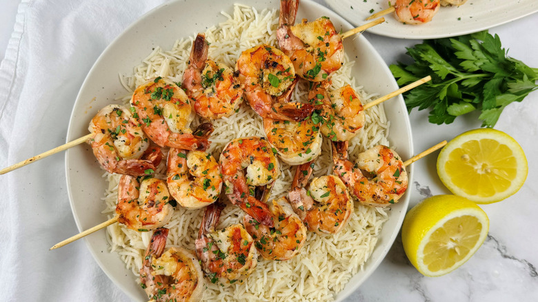 grilled skewered shrimp on plate with rice and lemons