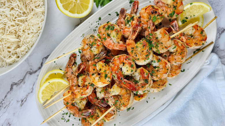 grilled shrimp skewers with lemon slices on plate