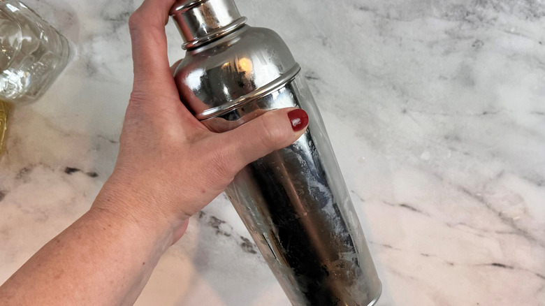 hand holding a lidded metal tumbler at an angle