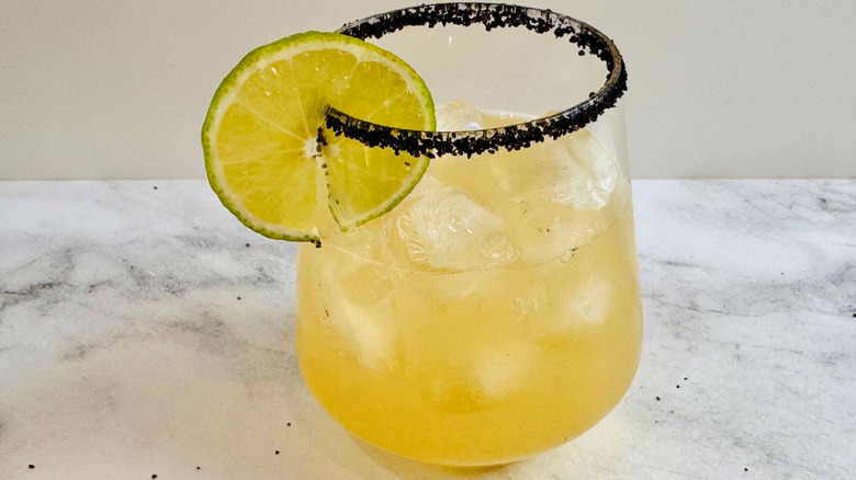 drink in a glass with a black salt rim and a lime garnish