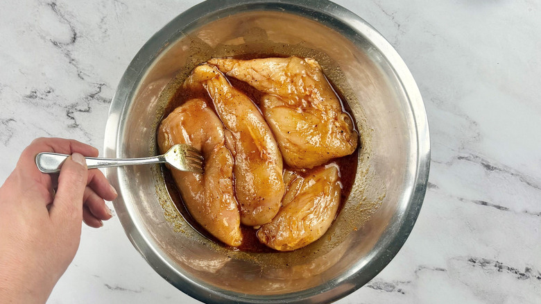 Chicken breasts coated in marinade in bowl