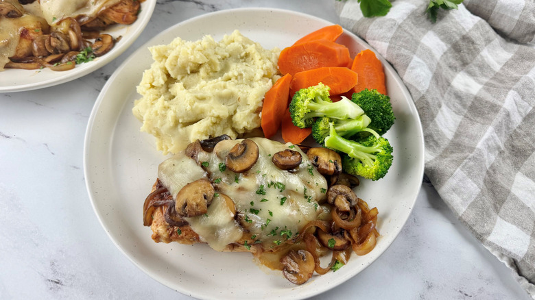 Smothered chicken with mashed potatoes and veggies on plate