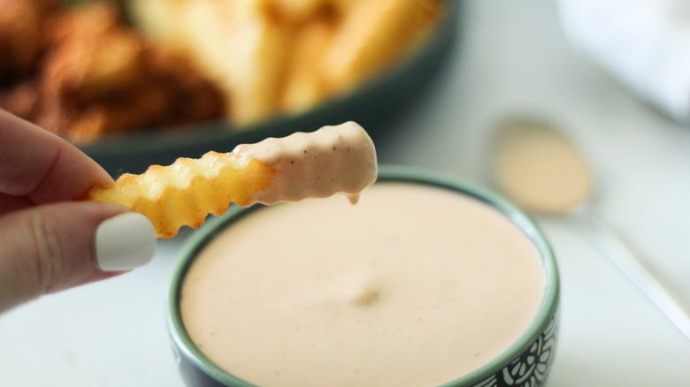 hand holding fry with sauce