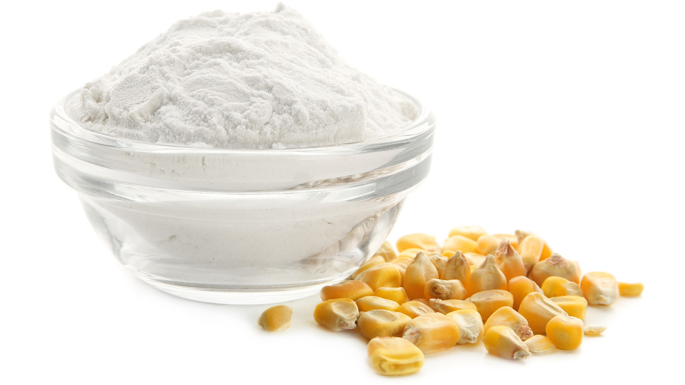 A glass bowl with corn starch and corn kernels next to the bowl