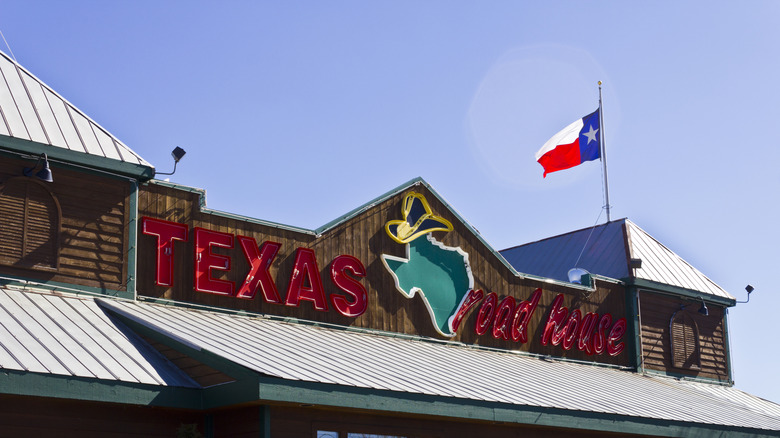 A Texas Roadhouse sign on a restaurant location with Texas flag