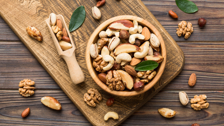 A variety of mixed nuts in bowl on cutting board