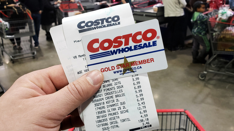 Person holding Costco membership card and receipt
