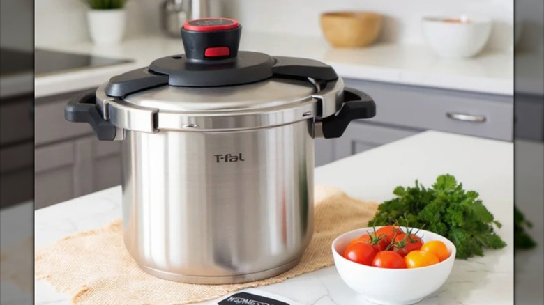 Pressure cooker on counter next to a bowl of tomatoes