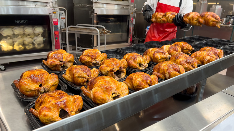Cooked rotisserie chickens at Costco being prepared for sale by employee