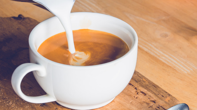 Pouring creamer into coffee