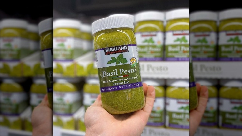 Hand holding Kirkland pesto jar