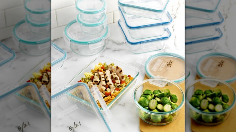 Collection of Snapware Pyrex storage containers with food in white kitchen.