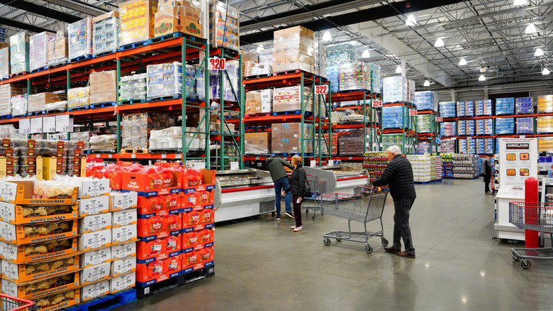 Members pushing shopping carts inside a massive Costco warehouse.