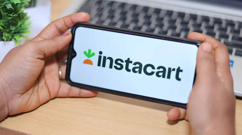 Hand holding a smartphone with Instacart on the screen