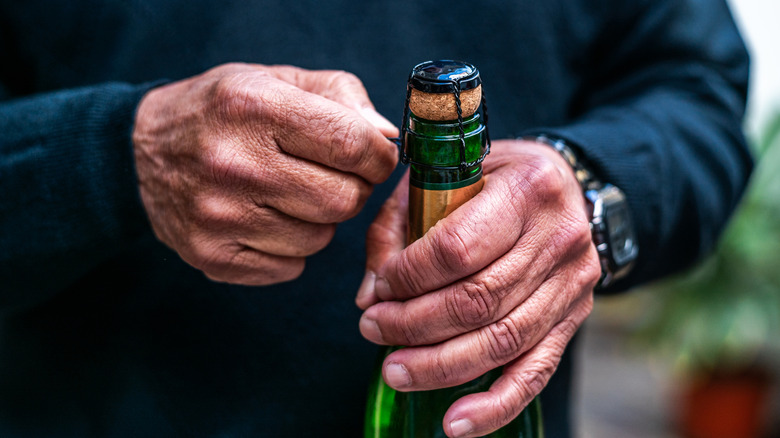 person opening bottle of Champagne or sparkling wine