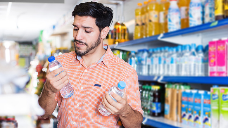 Person comparing bottles of water