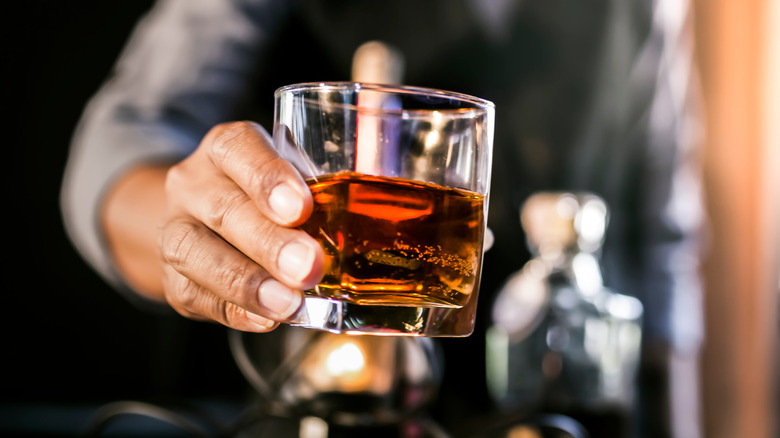 Bartender holding out glass of scotch