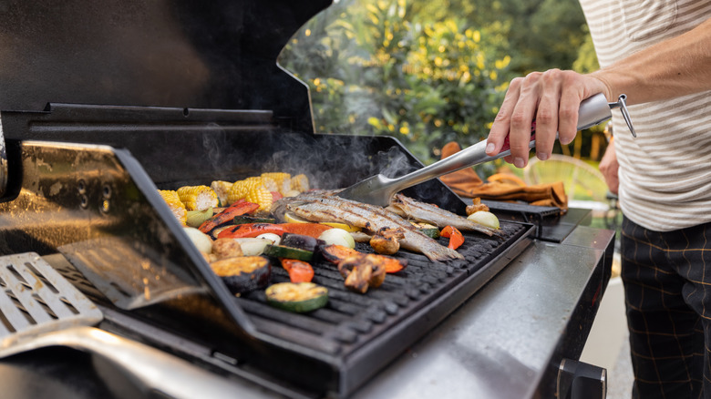 person grilling fish and veggies