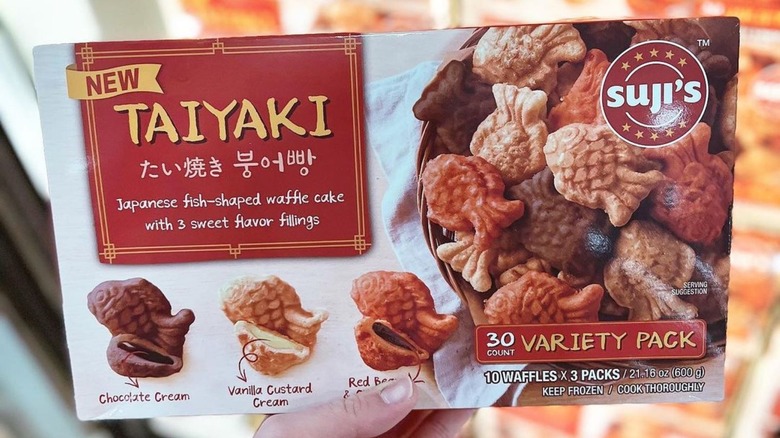 A hand holding a box of taiyaki
