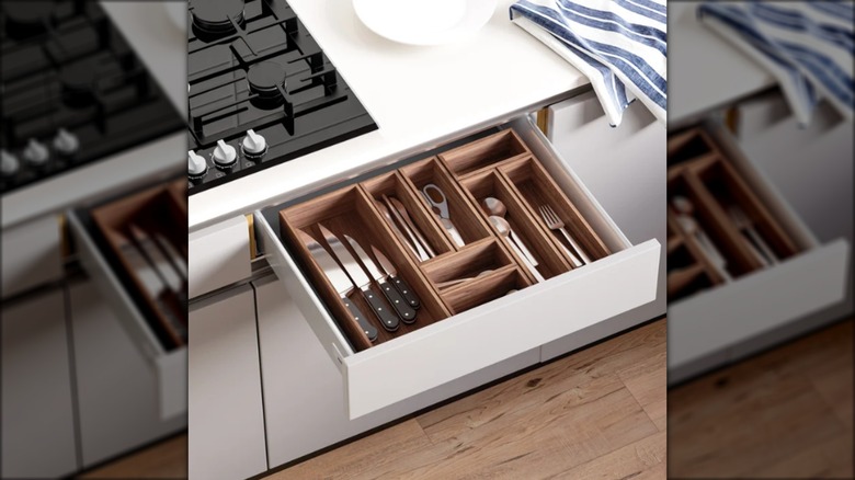 Open kitchen drawer with wooden dividers containing utensils