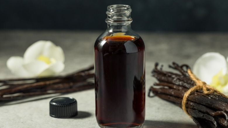 Bottle of vanilla extract next to beans