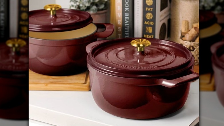 Two round, dark red Enameled Cast Iron Dutch Ovens with gold-toned knobs on top