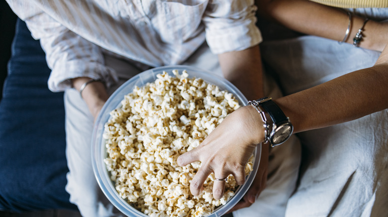 person digging in bowl of popcorn