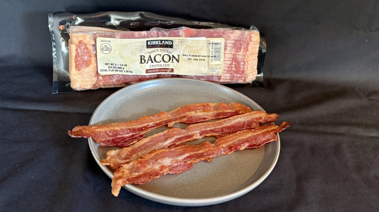 Kirkland thick cut bacon package behind plate of cooked bacon