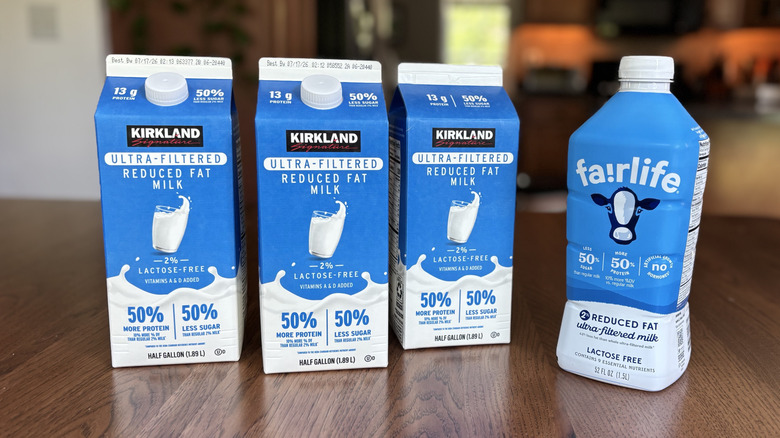 Three cartons of Kirkland Signature ultra-filtered milk next to a bottle of Fairlife milk