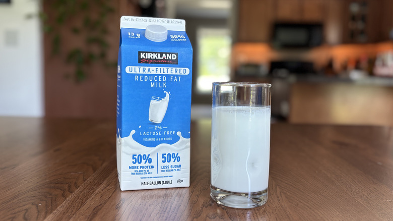 Carton of Kirkland Signature ultra-filtered milk next to a glass of milk
