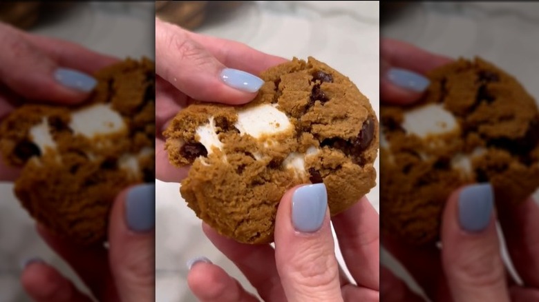 hand with blue fingernails breaks apart costco s'more cookie