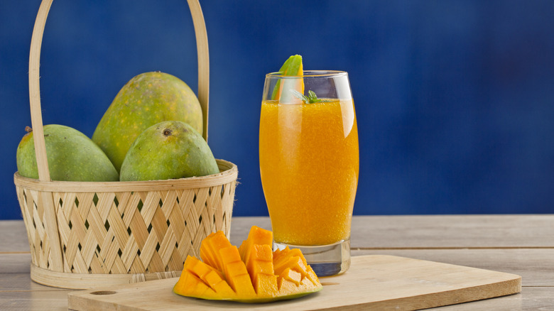 Mango smoothie next to fresh mangoes