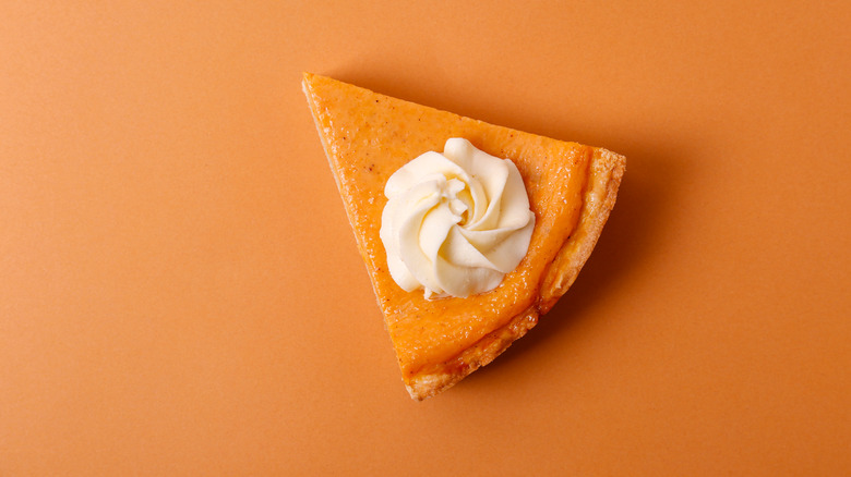 Slice of pumpkin pie with whipped cream on top