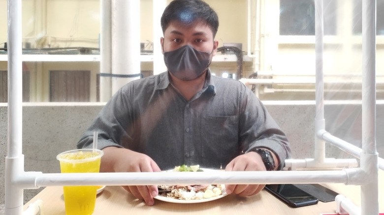 Person eating meal behind barrier