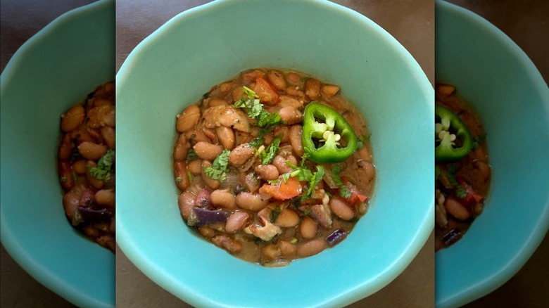 Bowl of homemade frijoles charros topped with cilantro and fresh jalapeño.